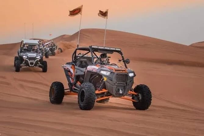 Dune buggies lined up on the sand at dusk
